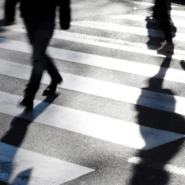 Blurry zebra crossing with pedestrians making long shadows